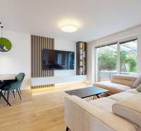 Living room in a 3-room apartment with a beige sofa and a dining table with green chairs.