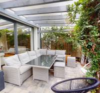 A terrace in a 3-room apartment with rattan seating and climbing plants.
