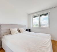 A bedroom in a 3-room apartment with a large window and a bed with a headboard.