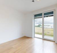 An empty room with a wooden floor and a large window in a 3-room apartment.