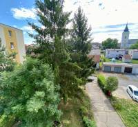A view of greenery and church towers in Očová from the window of a 4-room apartment.