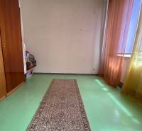 A spacious room with a green floor, carpet, and colorful curtains in a 4-room apartment.