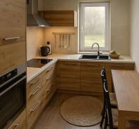A kitchen in a family house with wooden furniture and a window, complemented by appliances and a sink.
