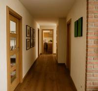 A hallway in a family house with wooden flooring, decorations on the walls, and a view into the kitchen.