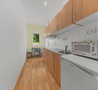 A family house kitchen with a microwave, refrigerator, and wooden cabinets, designed for practical use.