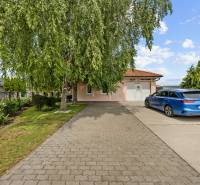 A family house on Kaštieľska Street in Veľký Biel surrounded by greenery and a parking lot.