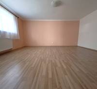 A spacious room with wooden flooring and an orange wall in a 4-room apartment.