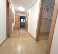 A hallway in a 4-room apartment with wooden doors and tiled flooring.
