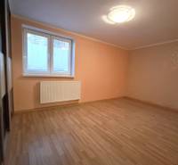 A room in a 4-room apartment with laminate flooring, orange walls, and a window with blinds.