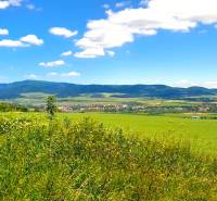 A view of agricultural and forest lands near Ražňany with mountains on the horizon.