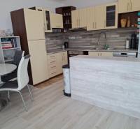 A kitchen in a 4-room apartment with a dining table, light wood, and white cabinets.