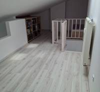 Attic room with stairs, wooden floor, and a bookshelf.