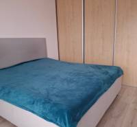 Bedroom in a 4-room apartment with a gray bed and a blue throw.