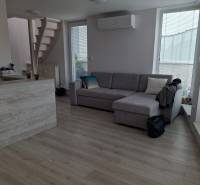 Living room with a sofa, stairs, and wooden floor in a 4-room apartment.