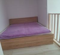 Simple bedroom with a wooden bed and a purple blanket in a 4-room apartment.