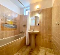Bathroom with a bathtub, sink, and a picture of a beach on the tiles in a 2-room apartment.