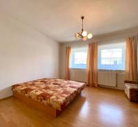 A bedroom with a ceiling light in a two-room apartment with two windows and a bed.