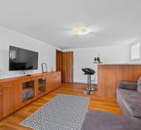 The photograph shows a cozy living room in a family house with wooden flooring.