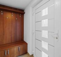 The hallway of a family house, a wooden coat rack, and white doors on Pluhová Street.