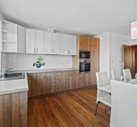 Kitchen and dining room with light cabinets and wooden floors, on Pluhová street.
