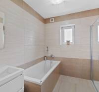 Bathroom in a family house on Pluhová street, with a bathtub and a shower.