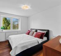 Bedroom in a family house on Pluhova Street with a bed and wooden floors.