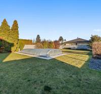 A beautiful garden with a covered swimming pool on Pluhová Street near a family house.