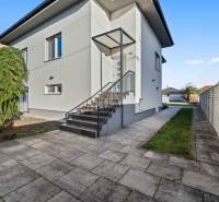 Family house on Pluhová Street, next to a sidewalk with concrete tiles and shrubs.