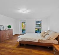 Bright bedroom in a family house with wooden flooring and a view of Pluhová Street.