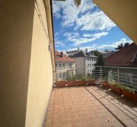 A balcony in a 5 or more room apartment with a view of the rooftops and blue sky.