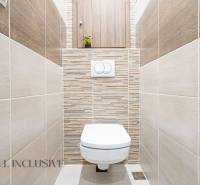 A toilet in a 3-room apartment with tiles in neutral shades.