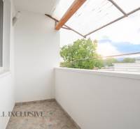 The balcony of a 3-room apartment in Gabčíkovo with a view of the surrounding trees and buildings.