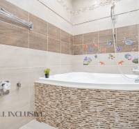 A bathroom in a 3-room apartment with a bathtub, decoration, and tiles in a colorful design.