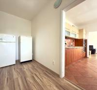 A kitchen in a 3-room apartment with a wooden floor and white appliances.