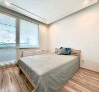 Bright bedroom in a 3-room apartment with a bed and wooden flooring.