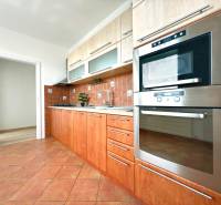 A kitchen of a 3-room apartment with brown tiles and built-in appliances.