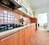 A kitchen with a gas stove, wooden cabinets, and brown tiles in a 3-room apartment.