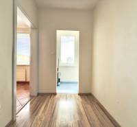 A hallway in a 3-room apartment with a wooden floor and a view of two rooms.