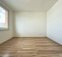A room with laminate flooring and a window in a 3-bedroom apartment.