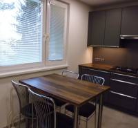 A kitchen in a 3-room apartment with a wooden table and four metal chairs.