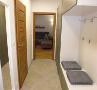 A hallway with a wardrobe wall leads to the living room in a 3-room apartment.