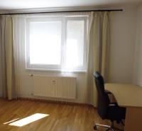 A room in a 3-room apartment with a wooden floor, a table, and a chair.
