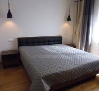 A bedroom with a large bed and two nightstands in a three-room apartment.