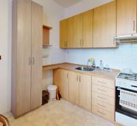A kitchen in a 2-room apartment with a wooden kitchen unit, a hob, and an electric kettle.