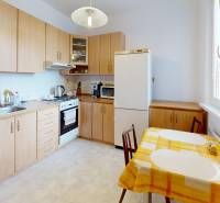A kitchen in a 2-room apartment with wooden cabinets, a stove, and yellow placemats.
