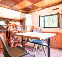 The interior of a cottage with furniture, a table, chairs, and an open window.