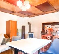 The interior of a cabin with a seating area, table, chairs, and wooden paneling on the ceiling.