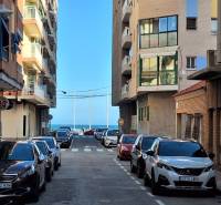 A street in the city of Torrevieja with a view of the sea, surrounded by apartment buildings.