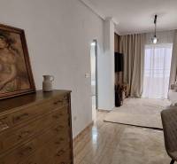 Living room in a 3-room apartment with paintings, furniture, and curtains.
