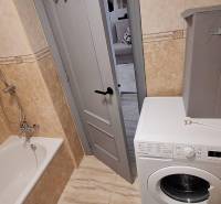 Bathroom with a bathtub, washing machine, and doors in a 3-room apartment.